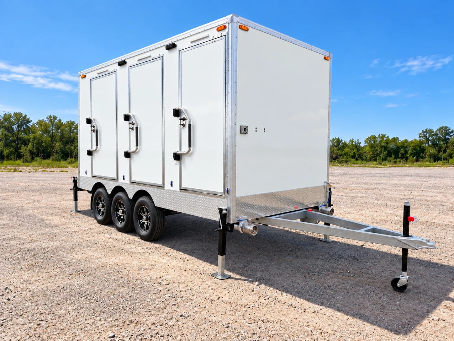 White three-door shower and restroom trailer parked on a gravel lot