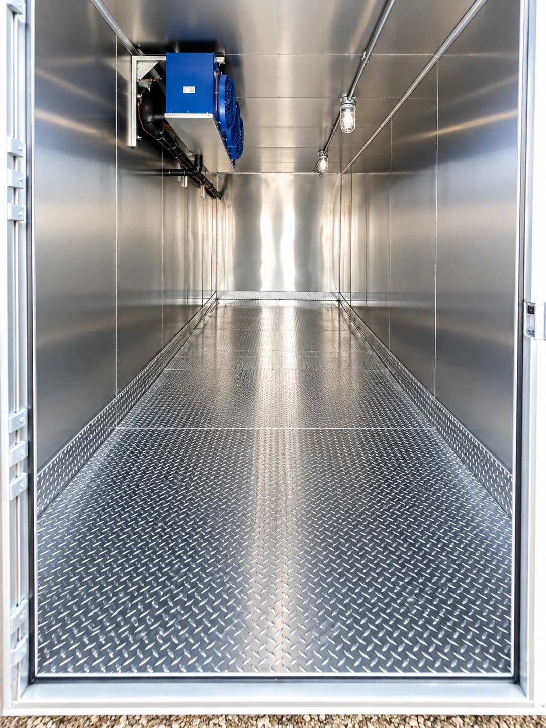 View through an open refrigerated trailer doorway toward the metal walls and overhead cooling unit