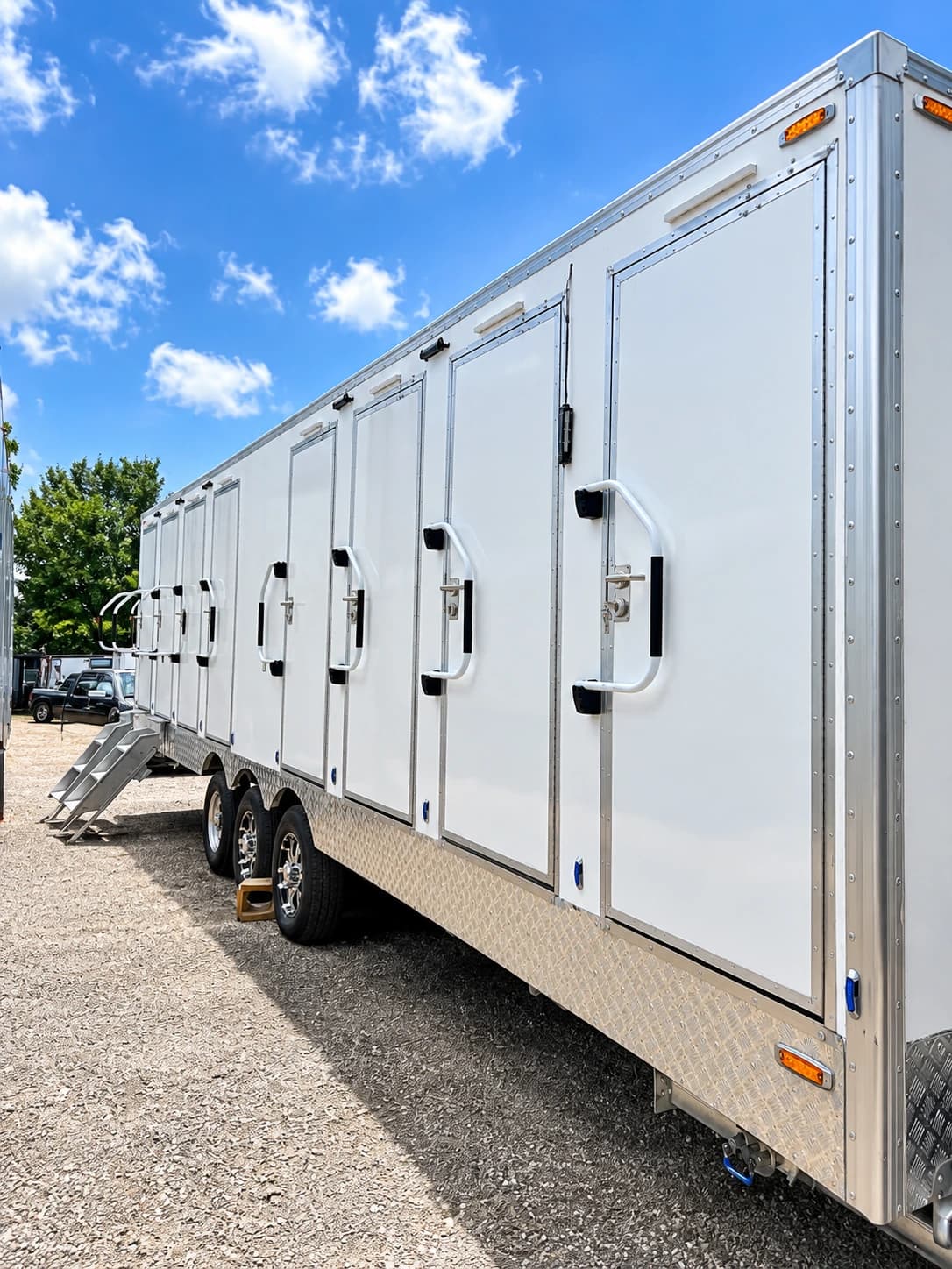 Side view along a white shower and restroom trailer with a row of exterior doors