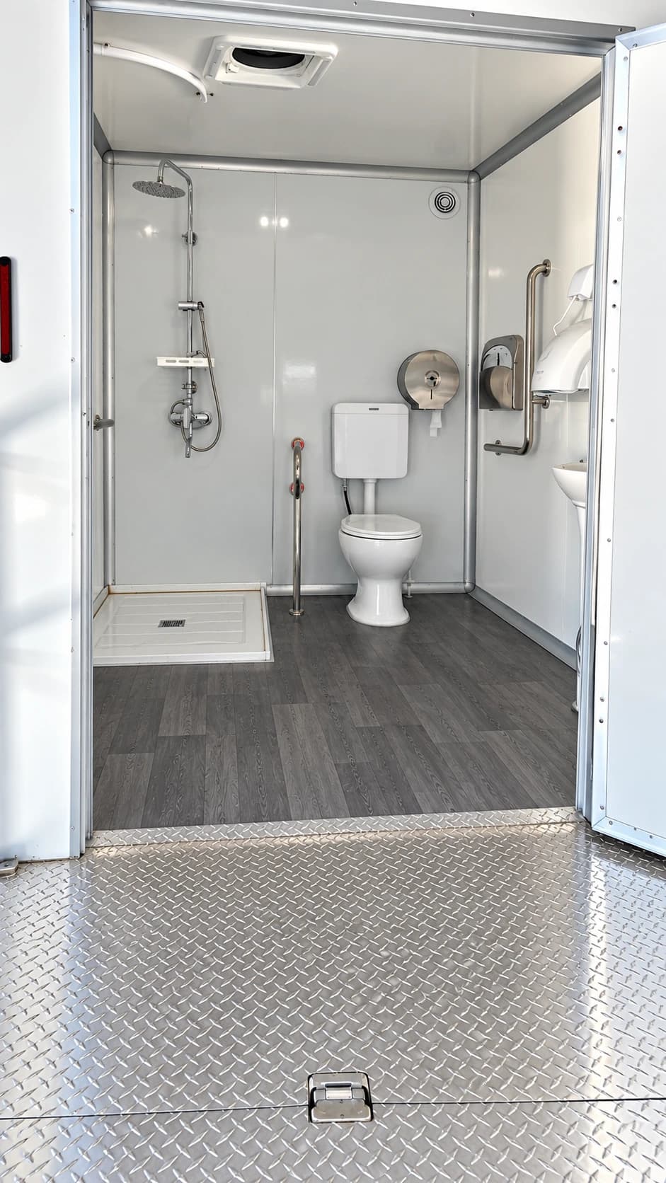 Shower and restroom interior with a toilet and grab rails