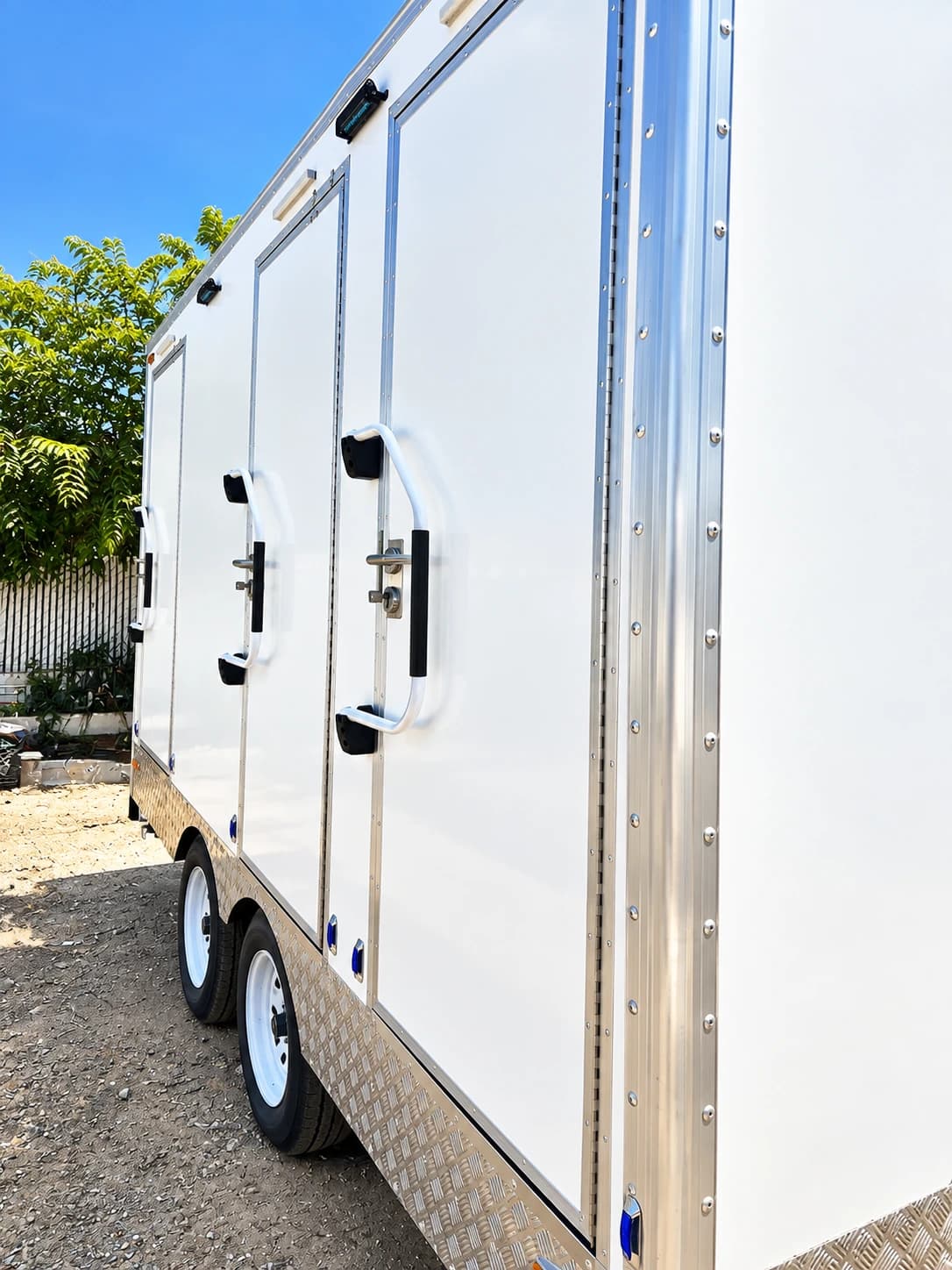 Close exterior view of a white trailer with separate doors and two axles