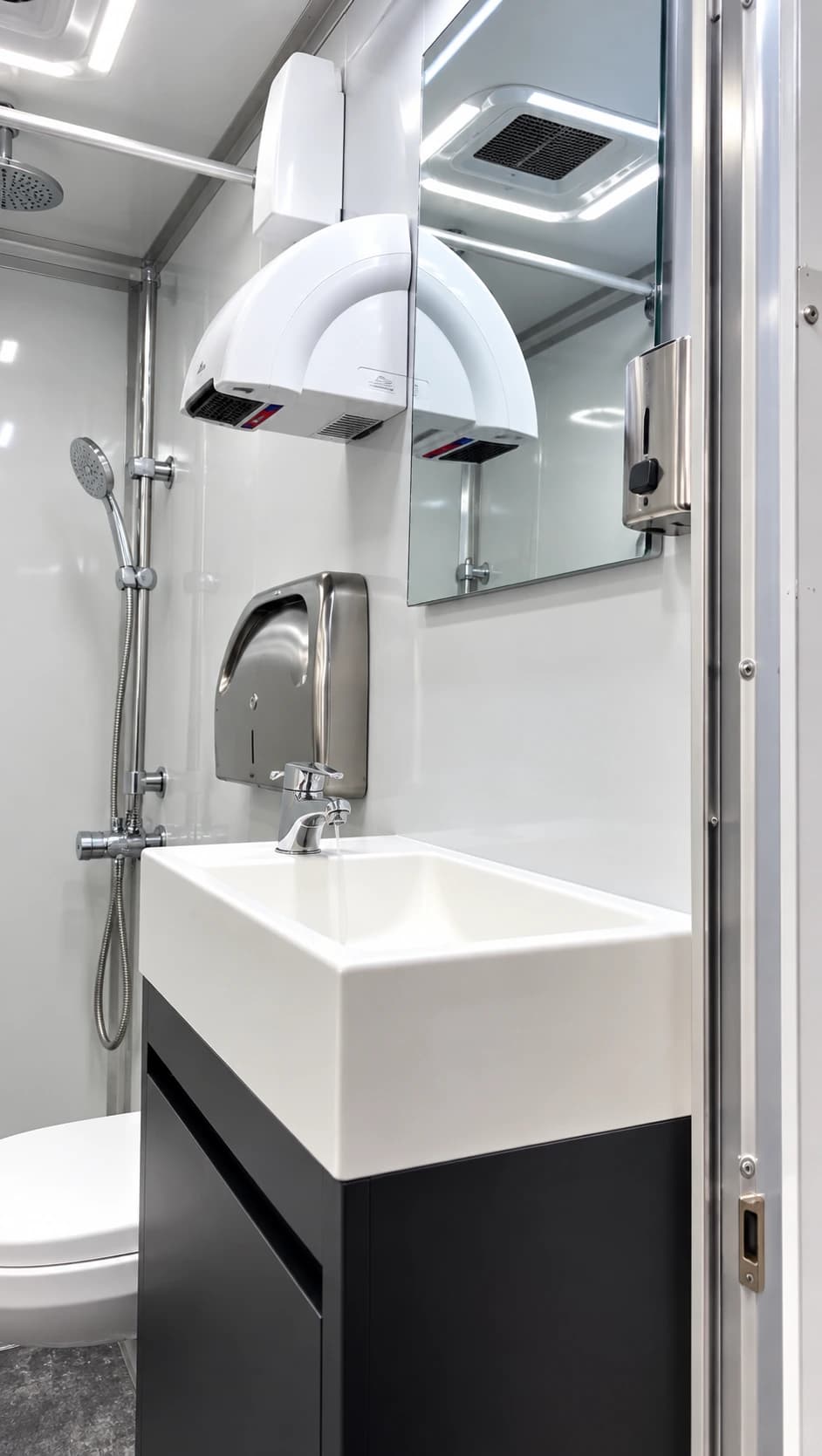 Vanity sink and wall mirror beneath an air-conditioning unit inside a restroom facility