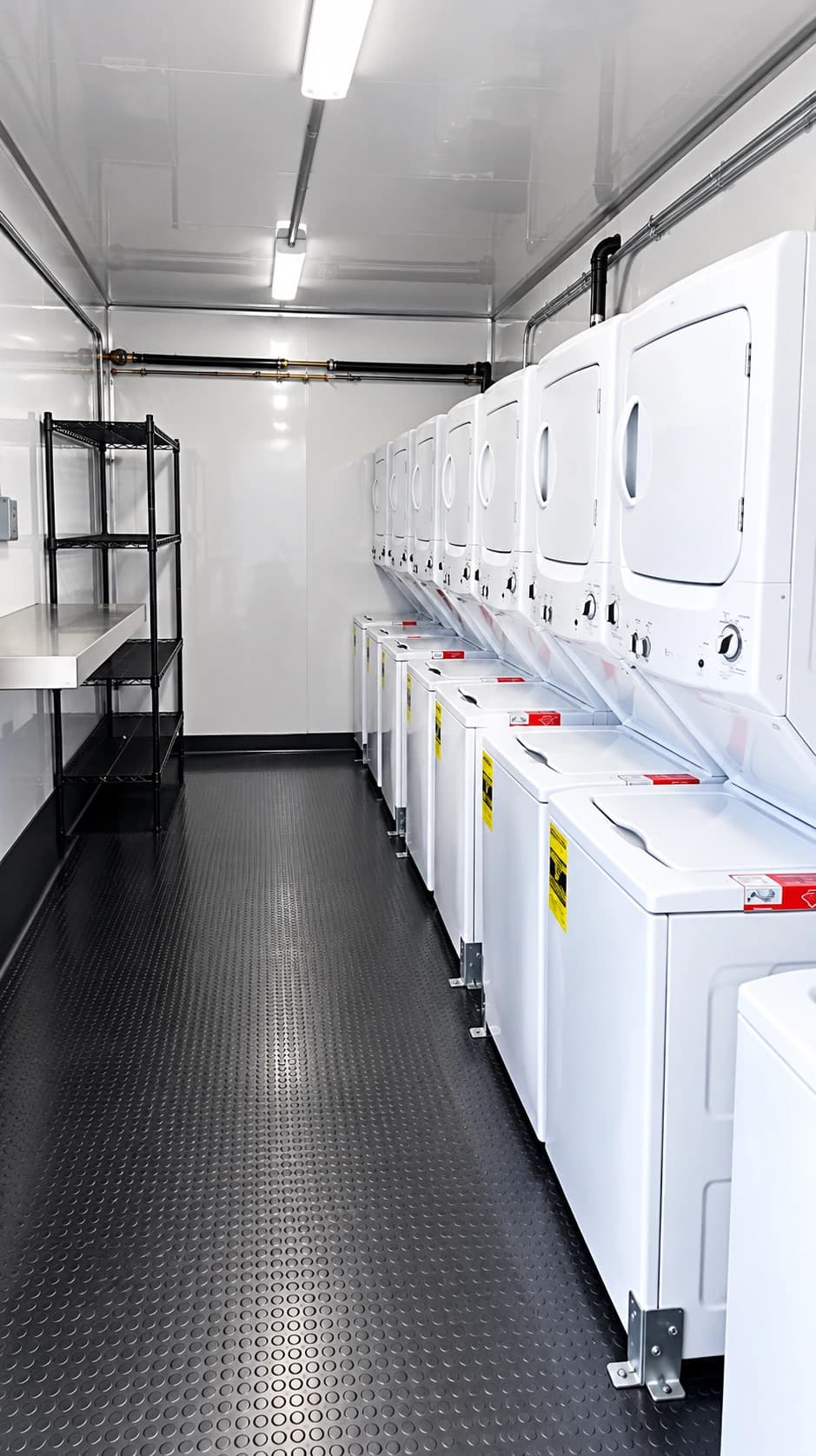Long row of white washing and drying machines opposite an open laundry trailer aisle