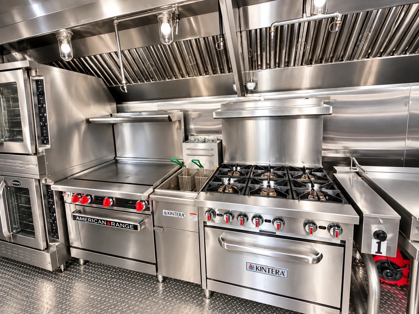 Stainless-steel cooking line with a griddle, gas range, fryer and overhead exhaust hood