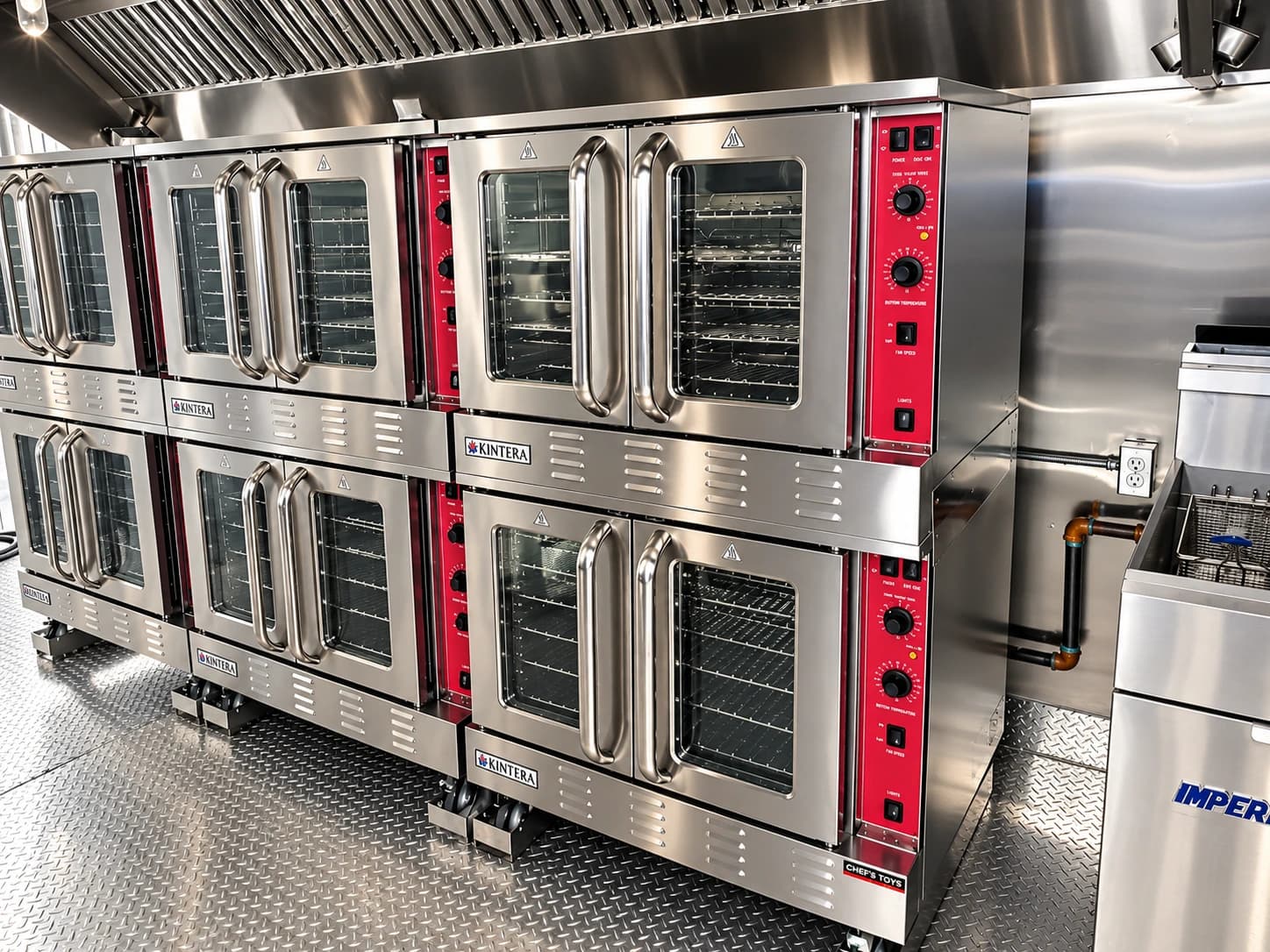 Bank of stacked commercial ovens with glass-fronted doors and red control panels